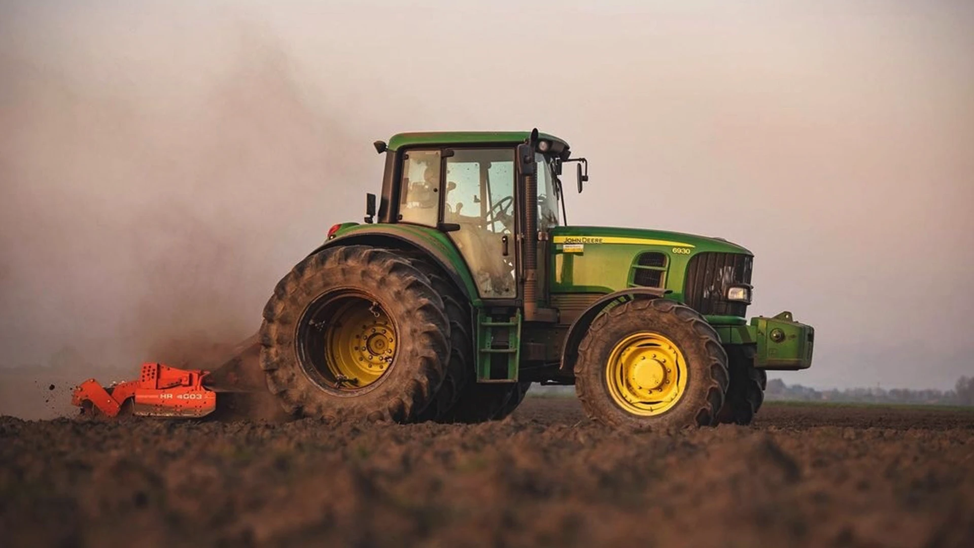 Green John Deere tractor ploughing a field